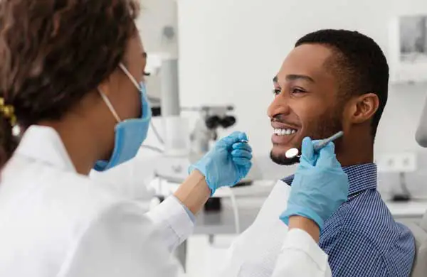 Young african guy smiling to his female dentist during crown consultation at Grins & Giggles Family Dentistry in Spokane Valley, WA Young african guy smiling to his female dentist during crown consultation at Grins & Giggles Family Dentistry in Spokane Valley, WA