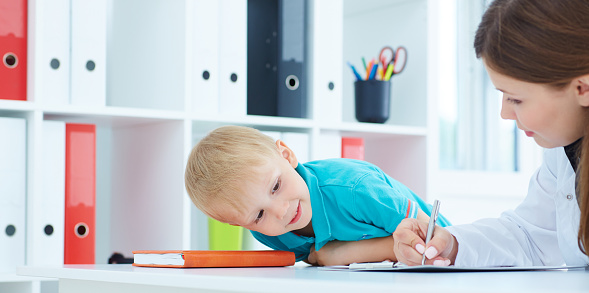 Woman filling out new patient forms while her young son watches at Grins & Giggles Family Dentistry in Spokane Valley, WA