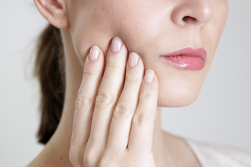 Woman with bruxism pressing at her aching jaw before going to Grins & Giggles Family Dentistry in Spokane Valley, WA